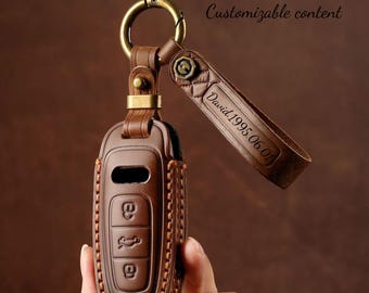 Könnte beinhalten: Braune Leder-Autoschlüssel-Hülle mit Metallring und Riemen. Die Hülle hat ein genähtes Design und Schlüsselsymbole. Der Riemen ist mit dem Text "David.1995.06.01" graviert.