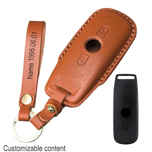 Peut inclure: Un étui de clé de voiture en cuir marron avec un porte-clés assorti. L'étui de la clé a une bordure cousue et un porte-clés. Le porte-clés porte l'inscription "Name.1995.06.01". Un porte-clés noir est également inclus.