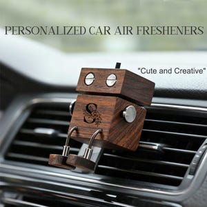 May include: A wooden robot-shaped car air freshener with the text "PERSONALIZED CAR AIR FRESHENERS" and "Cute and Creative". The robot has a dark wood finish, silver accents, and a floral initial design.