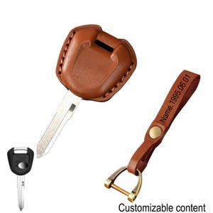 Puede incluir: Un llavero de cuero marrón con una llave y una funda a juego. El llavero tiene un cierre de metal dorado y una correa con el texto "Name 1995.06.01". La funda está cosida y se adapta a la llave.