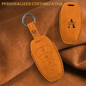 May include: Orange leather key fob cover with a silver ring and the text "PERSONALIZED CUSTOMIZATION" at the top. The cover has a button closure and a debossed design of the key buttons. A second cover is shown with the letter "A" and the name "ALEPPI".