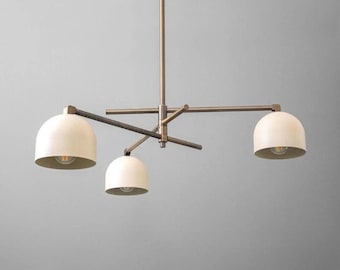 May include: A modern chandelier with a bronze finish and three off-white dome-shaped shades. The light fixture has a central stem and horizontal arms extending to hold the shades. The design is minimalist and suitable for various interior styles.