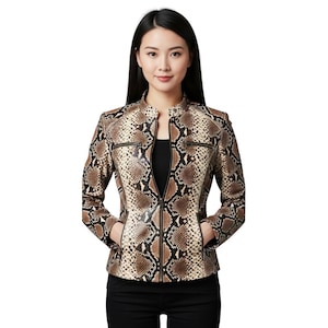 Pode incluir: Casaco castanho e bege com padrão de pele de cobra, com gola alta e fecho de correr completo. O casaco tem dois bolsos com fecho e é usado sobre um top preto. A modelo usa calças pretas.