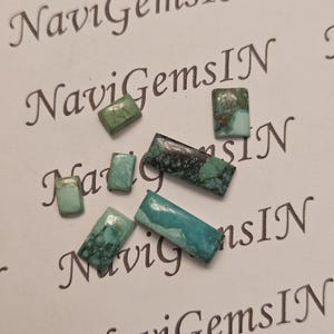 Peut inclure: Plusieurs pierres précieuses rectangulaires en turquoise, dans des tons de bleu et de vert. Les pierres sont disposées sur une surface blanche avec le texte "NaviGemsIN" imprimé.