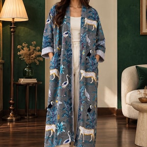 May include: A long, open-front grey duster coat featuring a vibrant jungle-themed print with leopards, toucans, and herons amidst blue palm leaves. The garment has long sleeves with grey and white striped cuffs and two deep side pockets.