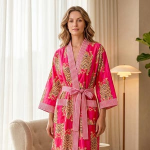May include: A vibrant pink robe with a tiger print design. The robe features a striped belt and trim, and is knee-length. The robe is made of a soft, flowing fabric, perfect for lounging. The robe is a stylish and comfortable addition to any wardrobe.