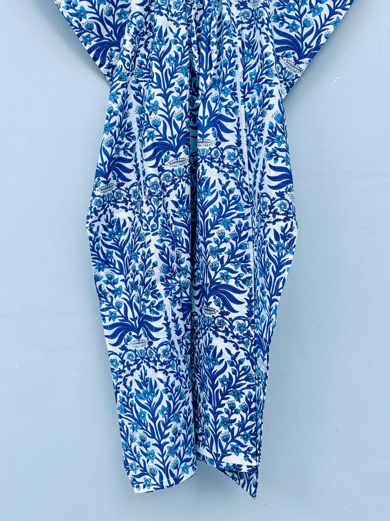 May include: A blue and white patterned garment with a floral design. The fabric features a repeating pattern of stylized leaves and flowers in varying shades of blue against a white background. The garment appears to be a loose-fitting dress or cover-up.