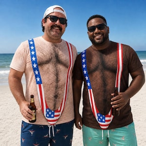May include: Two crew neck t-shirts featuring a realistic printed design of a hairy chest and a patriotic American flag-themed thong-style suspender graphic. The shirts are worn with dark blue and light teal patterned swim trunks and sunglasses.