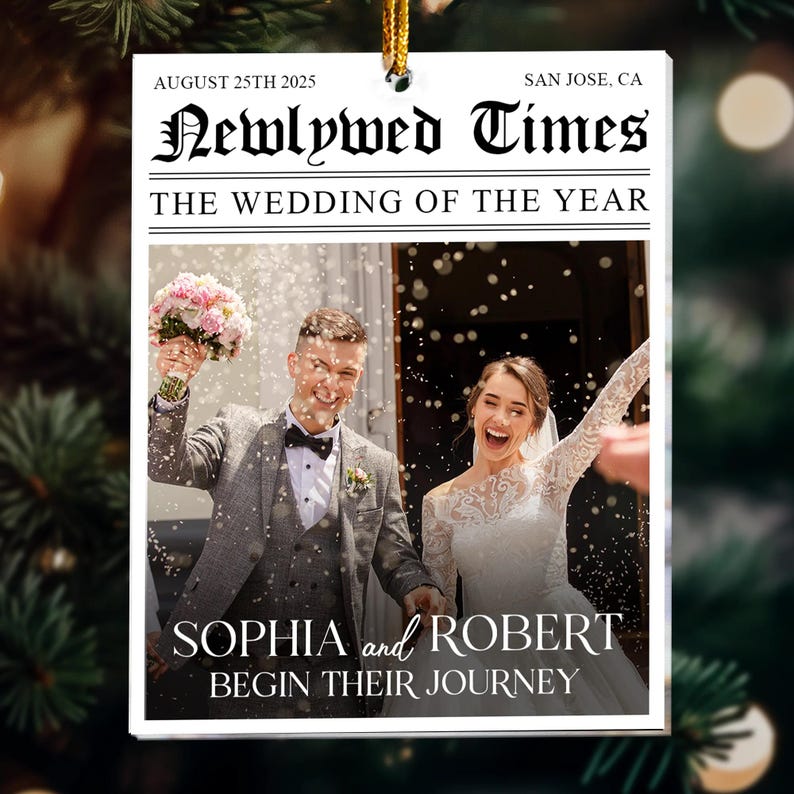 May include: A wedding-themed ornament with a newspaper design. The headline reads "Newlywed Times" with the date August 25th, 2025, and the location San Jose, CA. The image shows a couple celebrating their wedding, with the names Sophia and Robert.