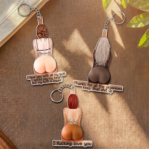 May include: Three acrylic keychains featuring illustrations of figures from behind. One has brown hair and text reading I love you with all my butt I would say my heart but my butt is bigger. Another has blonde hair and text reading Thanks for all the organisms keep that shit up. The third has red hair and text reading I fucking love you.