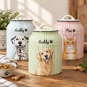 May include: Three ceramic storage canisters with lids, each featuring vertical stripes and a pet illustration. The blue canister shows a Dalmatian labelled Buddy, the green canister shows a Golden Retriever labelled Buddy, and the pink canister shows an orange tabby cat labelled Max.