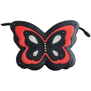 May include: A black and red butterfly-shaped bag with silver and gold accents. The bag features a detailed design with a zipper closure and a black strap. The bag is made of leather and has a unique, eye-catching design.