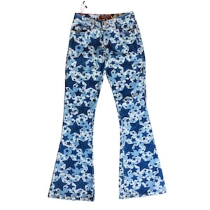 Può includere: Jeans blu con un motivo a stelle nelle tonalità del blu e del bianco. I jeans hanno un design a zampa e un classico stile a cinque tasche. I jeans hanno un'etichetta rossa sulla tasca posteriore.