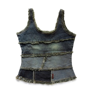 Könnte beinhalten: Jeans-Tanktop mit Patchwork-Design. Das Oberteil hat eine Mischung aus hell- und dunkelblauen Jeans-Einsätzen mit ausgefransten Kanten und einem kleinen roten Etikett. Die Träger und der Ausschnitt sind ebenfalls mit ausgefranstem Denim versehen.