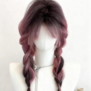 May include: A two-toned wig with dark brown roots that fade into a light pink hue. The wig features long, braided pigtails and a fringe. The wig is displayed on a mannequin head.