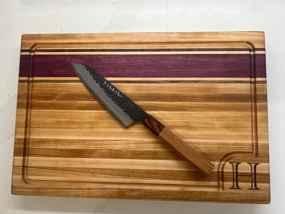 Handcrafted hardwood butcher block with real wood grain artistry — at $150 it signals genuine woodworking craft, not a laser-blasted blank.