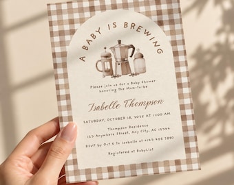 May include: A rectangular baby shower invitation card featuring a brown and white gingham border. The center displays an arched design with the text A BABY IS BREWING, illustrations of a French press, moka pot, and baby bottle, and event details.