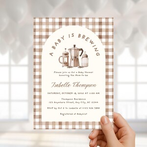 May include: A baby shower invitation with a brown and white gingham pattern border. The invitation features the text "A Baby is Brewing" above illustrations of coffee-making equipment. The invitation includes the name Isabelle Thompson and event details.