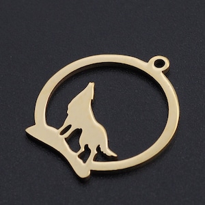 May include: Gold-toned metal charm featuring a wolf silhouette howling at the moon. The charm is circular with a cutout design and a small loop for attaching to a necklace or bracelet.