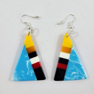 May include: A pair of triangle-shaped earrings with a blue, white, red, black, yellow, and orange geometric pattern.