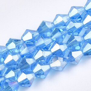 May include: A strand of light blue faceted glass beads. The beads are iridescent and have a slightly rounded shape.