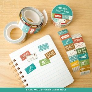 May include: An assortment of snail mail-themed sticker rolls and tape. The tape and stickers display colourful designs of envelopes, stamps, and the text "Snail Mail." A spiral notebook with matching stickers is also present.
