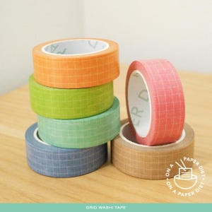 May include: A selection of grid washi tape rolls in various colours, including orange, green, blue, and pink. The tape is arranged to display the different shades and patterns. The text "GRID WASHI TAPE" is visible at the bottom.