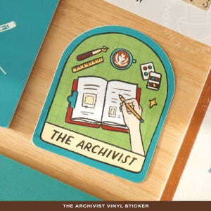 May include: A vinyl sticker with a green background and a teal border. The sticker features a drawing of an open book with a hand holding a pencil, a coffee cup, and the text "THE ARCHIVIST".