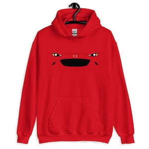 May include: Red hooded sweatshirt with a car face design. The graphic features headlights, a black grille, and a circular emblem. The sweatshirt has a front pocket and a drawstring hood, suitable for casual wear.