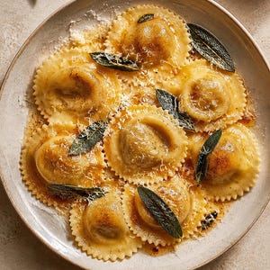 Può includere: Un piatto di ravioli rotondi dai bordi smerlati ricoperti da una salsa al burro dorata, guarniti con foglie di salvia verde scuro croccanti e una leggera spolverata di formaggio bianco finemente grattugiato su un piatto di ceramica.