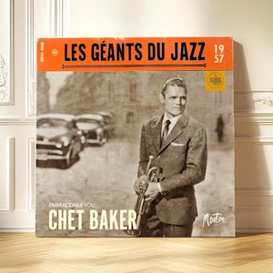 May include: A framed album cover featuring Chet Baker, with the text "LES GÉANTS DU JAZZ" and "1957". The cover art is in black and white, showing Baker holding a trumpet. The album is displayed on a wooden floor.