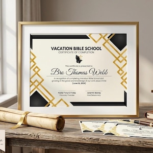 May include: A framed Vacation Bible School certificate of completion for Bro Thomas Webb dated June 18, 2026. The document features black and gold geometric borders, a black praying hands icon, and signatures from Pastor Tony E. Fraley and Janet M. Murrey.
