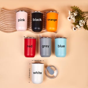 May include: Seven cylindrical tumblers in pink, black, orange, red, grey, blue, and white, each labeled with its color. The white tumbler is shown with a clear lid and dimensions of 11.5cm (4.53 inches) in height and 7.6cm (2.99 inches) in width.