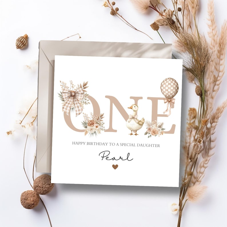 May include: A birthday card with the word "ONE" in tan letters, decorated with floral and bow accents. A cartoon duck is featured. The text "HAPPY BIRTHDAY TO A SPECIAL DAUGHTER" and the name "Pearl" are also included.