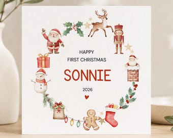 Op de afbeelding: Een vierkante witte wenskaart met een aquarelkrans van kersticonen, waaronder de kerstman, een rendier, een notenkraker, een sneeuwpop, een peperkoekmannetje, cadeautjes en een kerstsok. De tekst luidt HAPPY FIRST CHRISTMAS SONNIE 2026.