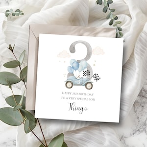 Puede incluir: Tarjeta de cumpleaños cuadrada con una ilustración de acuarela. La tarjeta presenta un gran número 3, un coche azul claro con globos y banderas a cuadros. El texto dice "Happy 3rd Birthday To A Very Special Son Thiago."