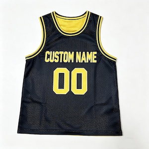 Può includere: Canotta da basket reversibile nera e gialla con la scritta "CUSTOM NAME" e il numero "00" in giallo. La canotta ha un design a rete e un bordo giallo.