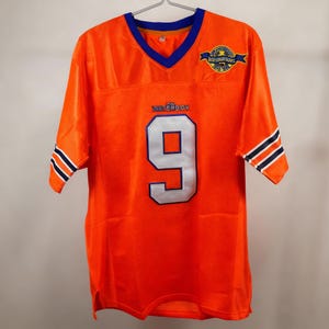 May include: Orange mesh jersey with blue and white detailing. The number 9 is displayed in white with a blue outline on the front. The text "THE WATERBOY" is above the number. The jersey has a blue V-neck and a patch that says "BOURBON BOWL" on the upper right.