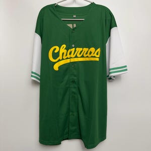 May include: Green baseball jersey with white sleeves and the word "Charros" in yellow script across the chest. The jersey has a button-down front and green and white striped cuffs.