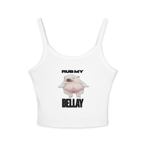 Pode incluir: Top curto branco com alças finas. A parte superior apresenta um gráfico de um cachorrinho rechonchudo com o texto "RUB MY" acima do cachorrinho e "BELLAY" abaixo, tudo em letras pretas. O cachorrinho é rosa claro e branco.