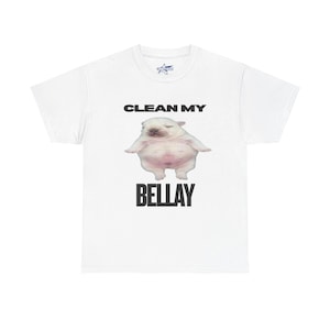 Pode incluir: Camiseta branca com uma imagem de desenho animado de um cachorrinho rechonchudo e o texto "CLEAN MY BELLAY" em preto. A camiseta tem gola redonda e mangas curtas.