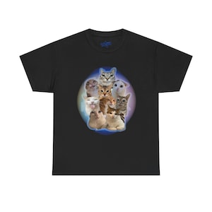 May include: Black t-shirt featuring a graphic of various cat faces arranged in a circle. The cats have different expressions and colors, set against a soft, gradient background. The shirt has a crew neck and short sleeves.