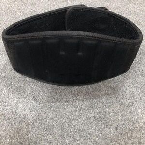 Puede incluir: Un cinturón de levantamiento de pesas negro con un diseño ancho y contorneado que presenta secciones acolchadas verticales en el exterior. El cinturón incluye un sistema de cierre de velcro seguro y una hebilla de metal reforzada.