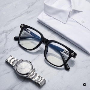 Könnte beinhalten: Schwarz gerahmte Brille mit silbernen kreuzförmigen Akzenten an den Bügeln, eine silberfarbene analoge Armbanduhr mit Metallgliederarmband und ein gefaltetes weißes Hemd mit Kragen. Die Gegenstände sind zusammen angeordnet und bilden ein Set.