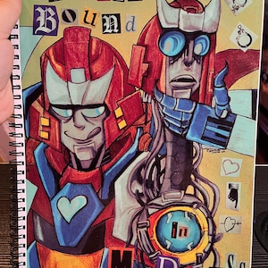 May include: Spiral-bound sketchbook featuring a colorful illustration of two robot characters. The robots are primarily red, blue, and silver, with the text "TOGETHER BOUND" and "in Madness" on the cover. The artwork includes hearts and other symbols.