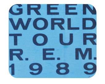 May include: A blue and white sticker with the text "GREEN WORLD TOUR R.E.M. 1989" printed in black.