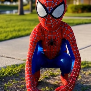 May include: A child wearing a Spider-Man costume, crouching on the grass. The costume is red and blue with a spiderweb pattern and a spider emblem on the chest. The mask has white eye coverings.