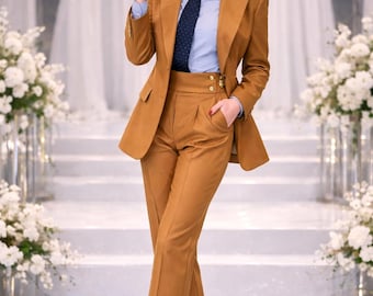 Op de afbeelding: Een op maat gemaakt, bruin pak met een bijpassende blazer en een broek met hoge taille. Het pak wordt gecombineerd met een lichtblauw overhemd en een stropdas met patroon. De outfit wordt afgemaakt met bruine hakken.