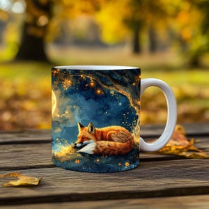 Könnte beinhalten: Weiße Keramik-Tasse mit einer Illustration eines schlafenden Fuchses unter einem Baum und einem Vollmond. Der Fuchs hat orange-weißes Fell, vor einem blau-goldenen Nachthimmel. Die Tasse steht auf einer Holzoberfläche.