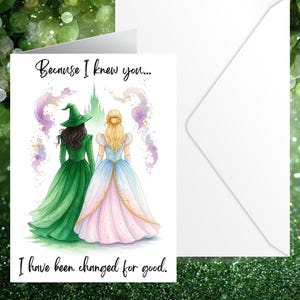 Könnte beinhalten: Grußkarte mit einer Aquarellillustration von zwei Frauen in Kleidern, eine grün und eine rosa und blau, mit einer Burg im Hintergrund. Der Text lautet: „Weil ich dich kannte... Ich habe mich zum Guten verändert.“